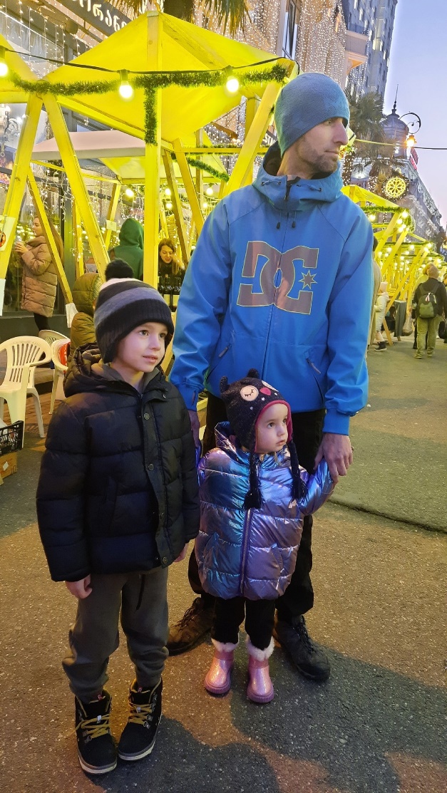 A person and two children standing in front of a yellow structureAI-generated content may be incorrect.